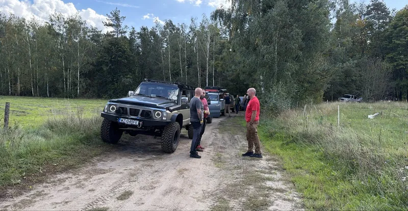 Nissan Patrol na piaszczystej drodze, załogi przy autach