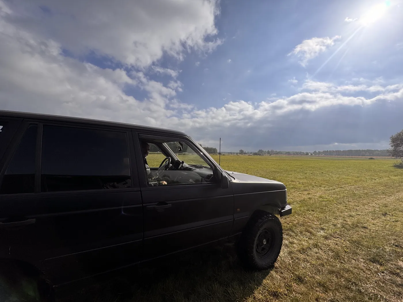 Range Rover na łące pod zachmurzonym niebem