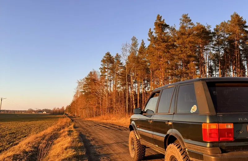 Range Rover na polnej drodze o zachodzie słońca