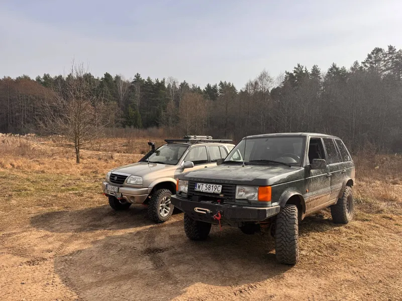 Suzuki Grand Vitara i Range Rover na piaszczystym placu